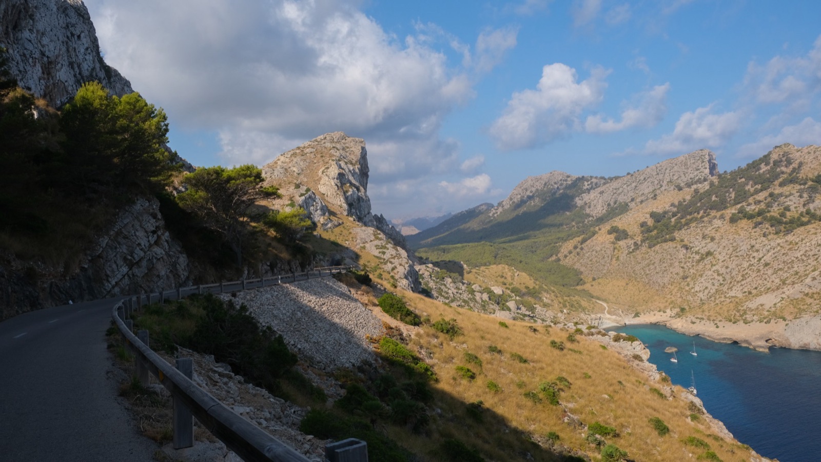 A coastal road winding between rocky mountains above the water.